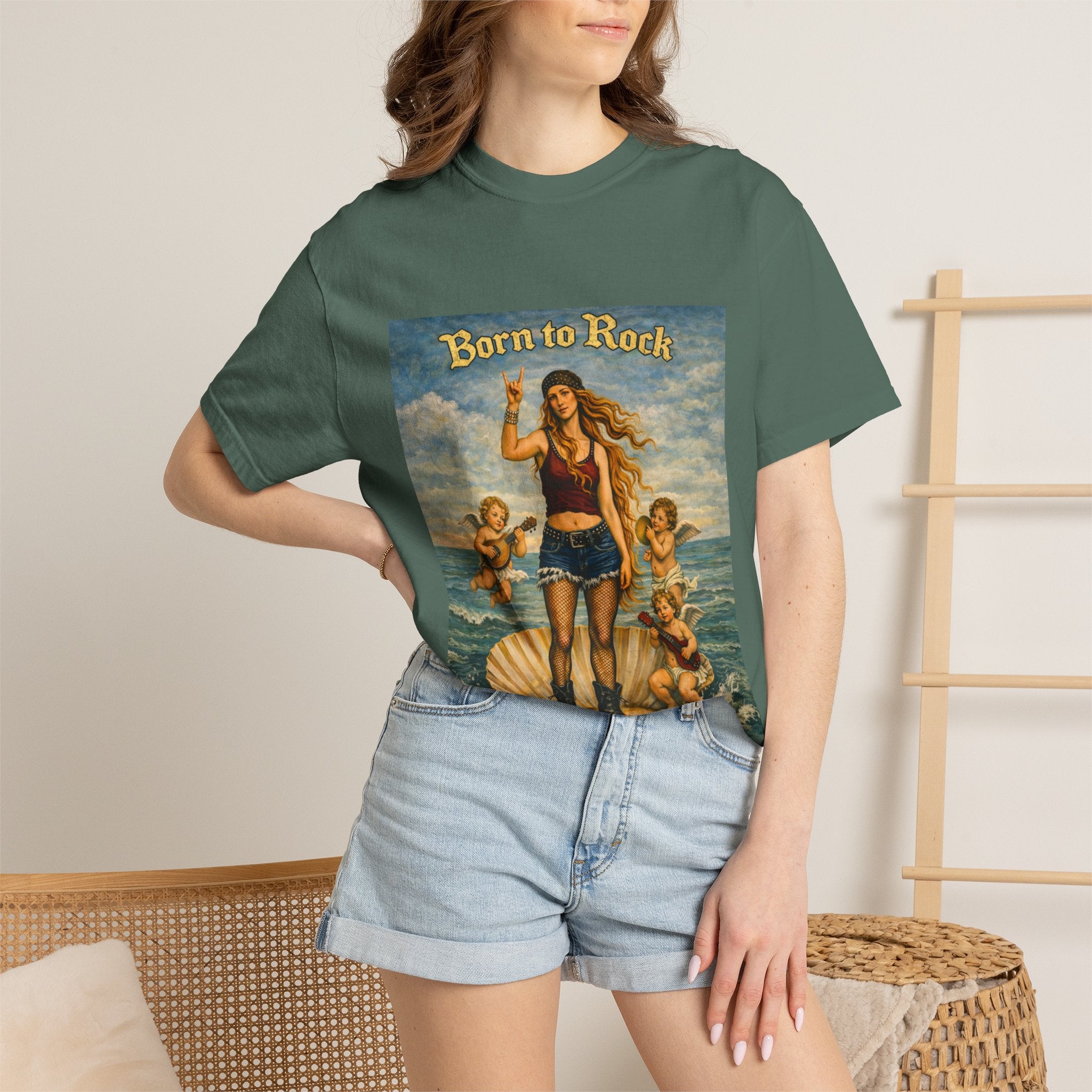 Woman wearing a Blue Spruce t-shirt showing a reimagined image of Botticelli's Venus with 'Born to Rock' graphic design on a background of wicker chair