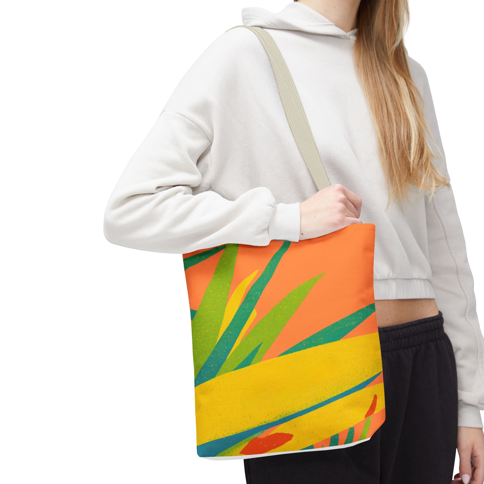 Person wearing a white hoodie holding a colorful tote bag with leaf design inspired by Ragged Point, St Philip, Barbados.