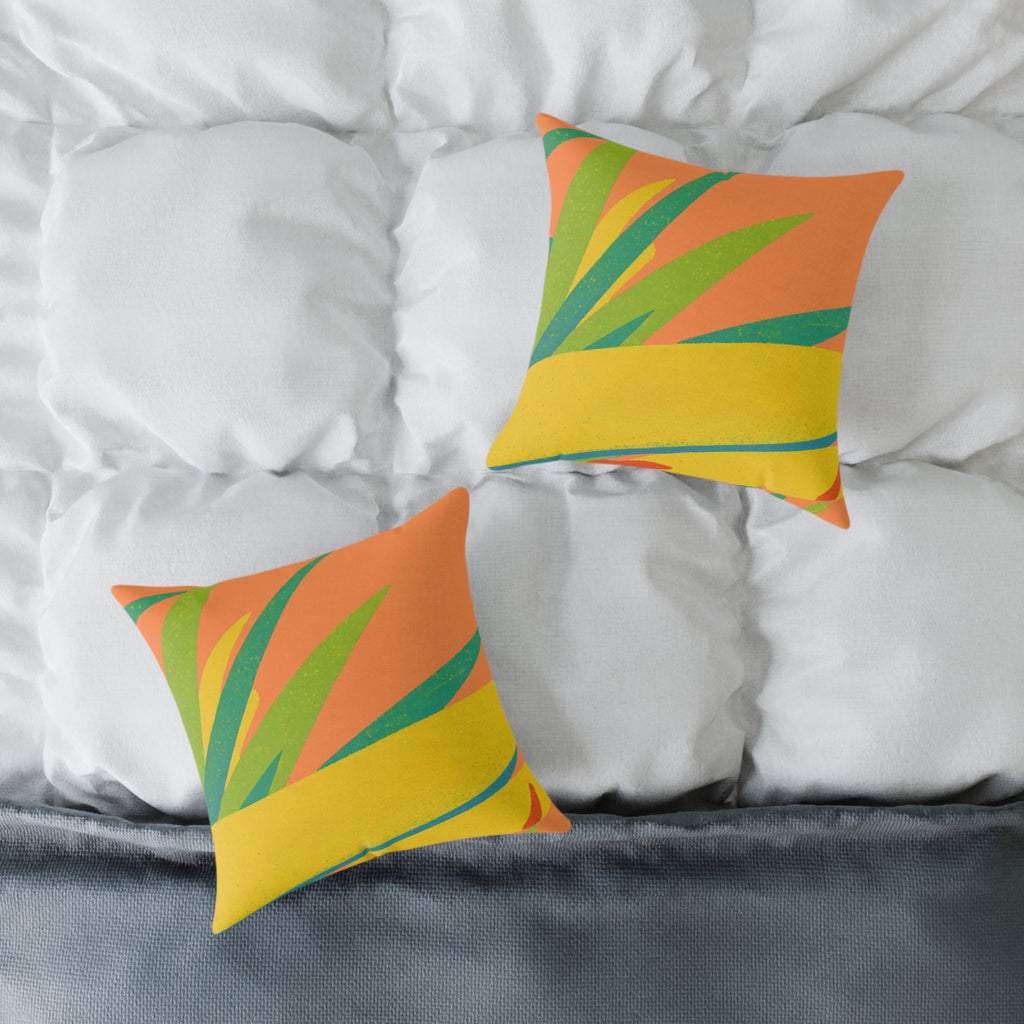 Two colorful pillows with leaf patterns on a bed with white bedding.