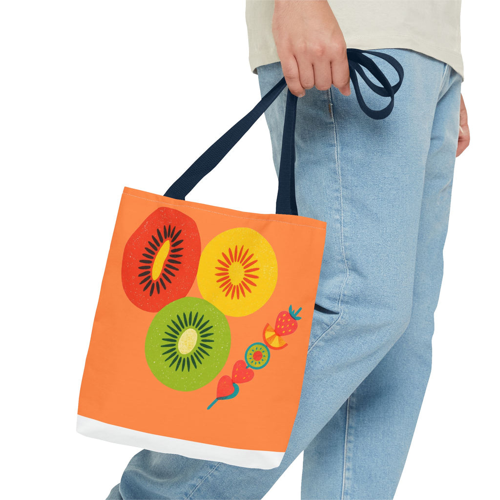 Person holding a colorful tote bag with fruit designs on a white background