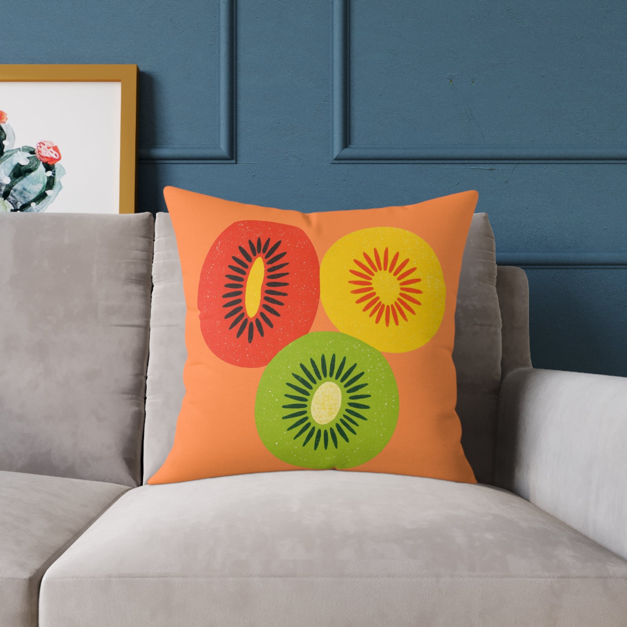Decorative pillow with colorful kiwi design on a gray sofa against a blue wall.