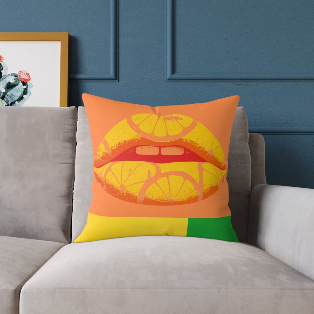 Colorful pillow with a lips and lemon design on a gray sofa against a blue wall.