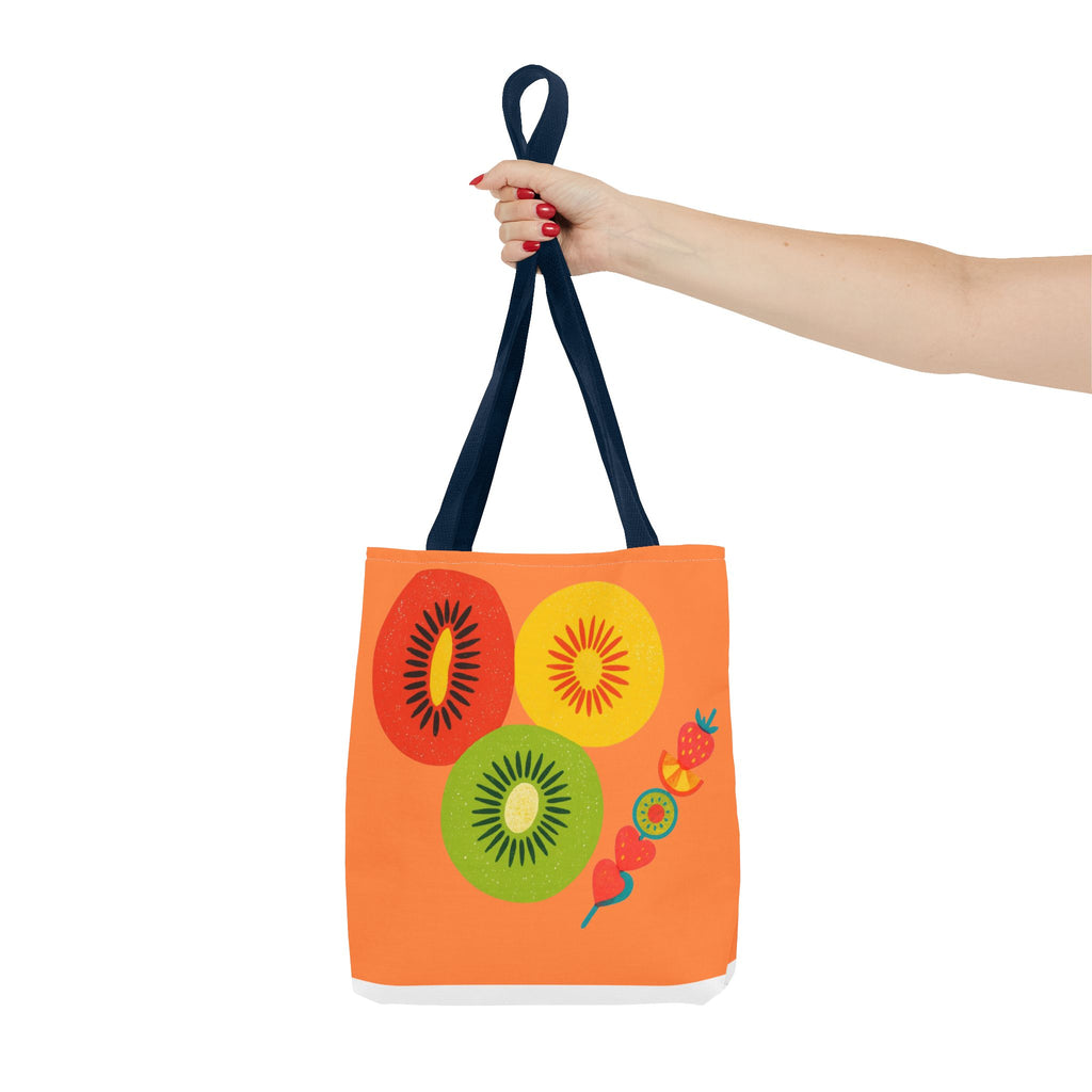 Orange tote bag with fruit design held by a hand on a white background