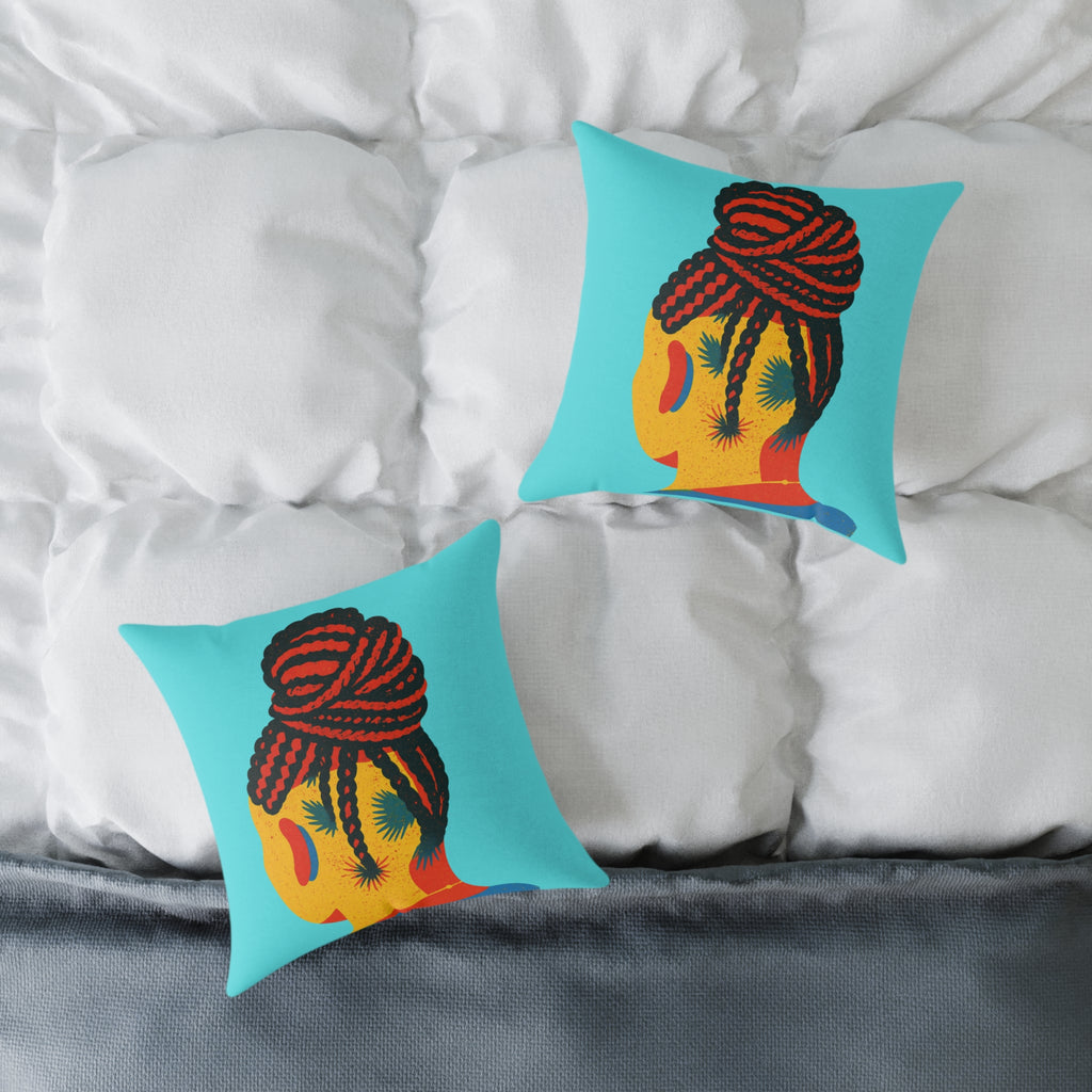 Two decorative pillows with a colorful design of a face with braided hair on a bed.