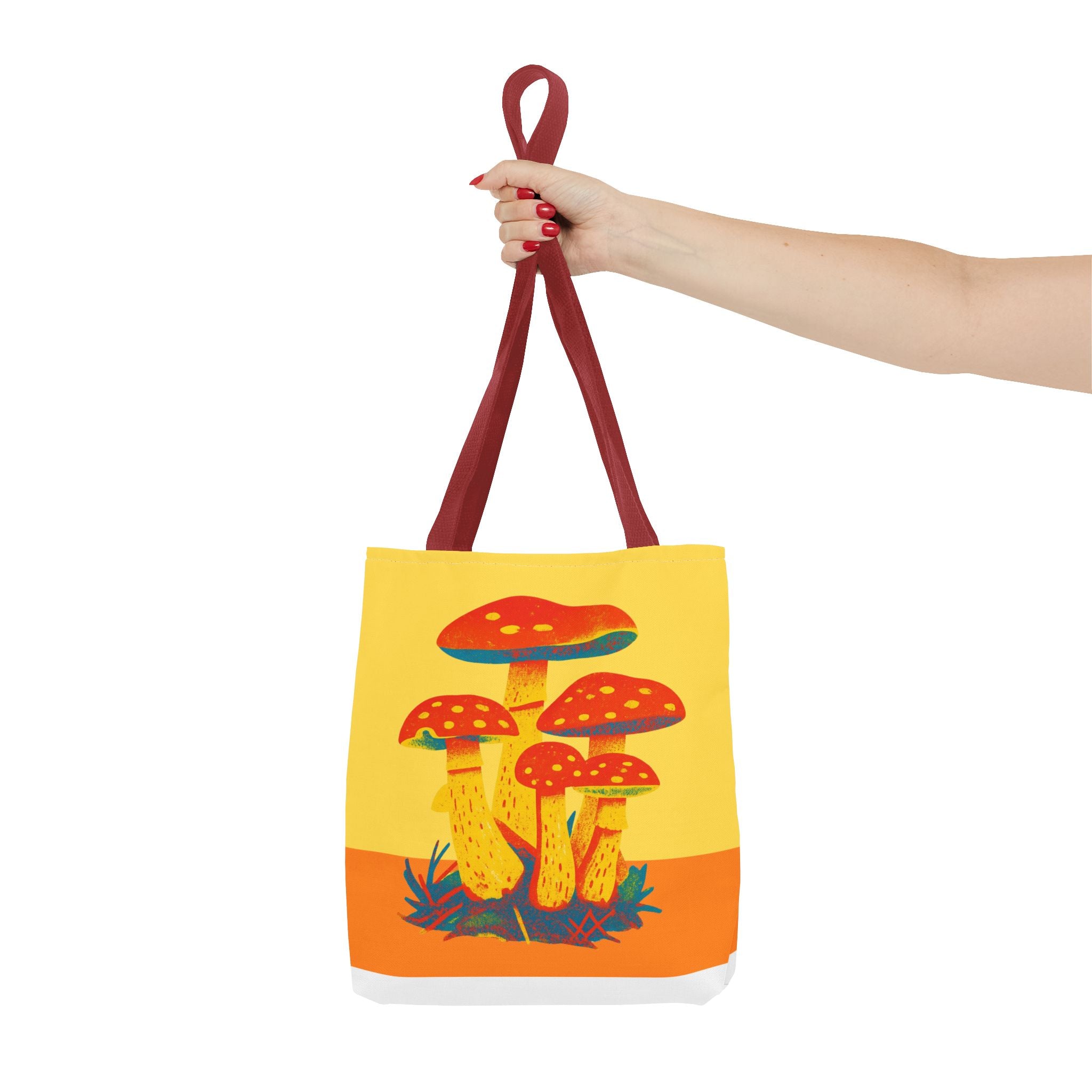 Tote bag with mushroom design held by a hand on a white background