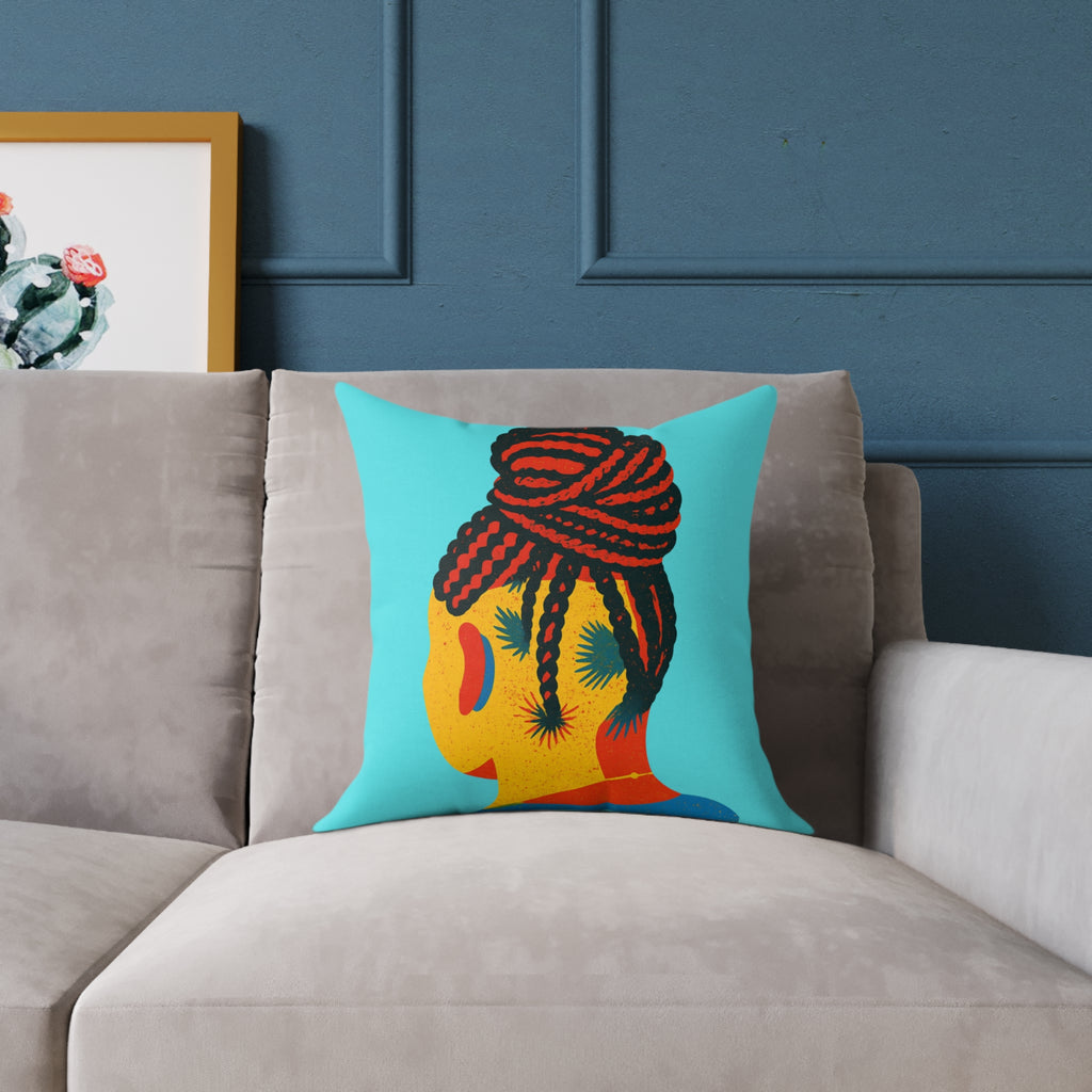 Colorful pillow with a braided hair design on a gray sofa against a blue wall.