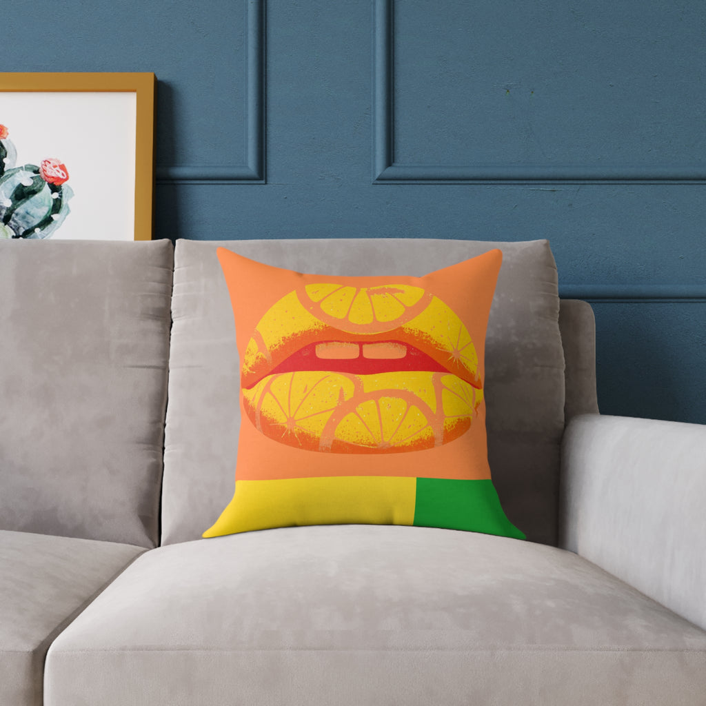 Colorful pillow with a citrus lips design on a gray sofa against a blue wall.