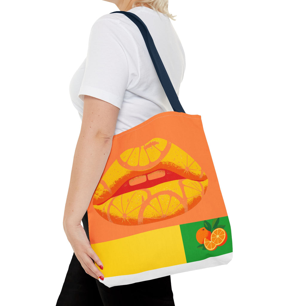 Person holding a tote bag with a colorful design of lips and oranges on a white background