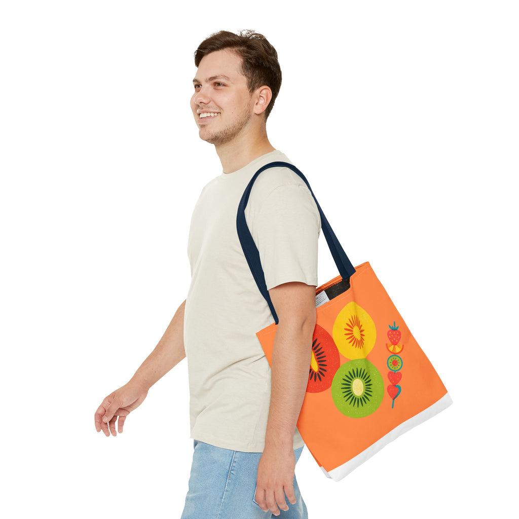 Man carrying an orange tote bag with colorful fruit design on a white background