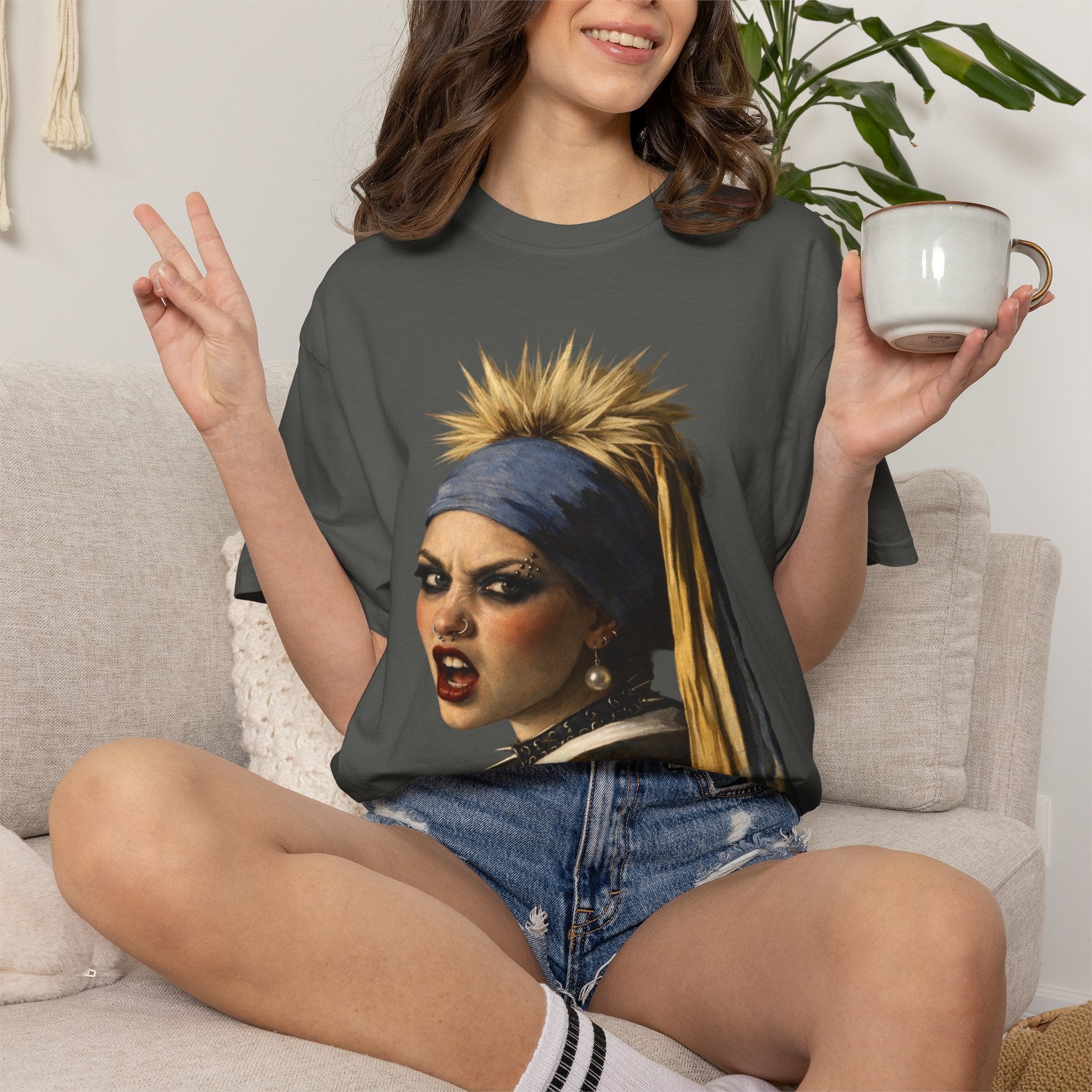 Person wearing a grey t-shirt with a reimagined image of Vermeer's girl with a pearl earring sitting on a stool against a white background