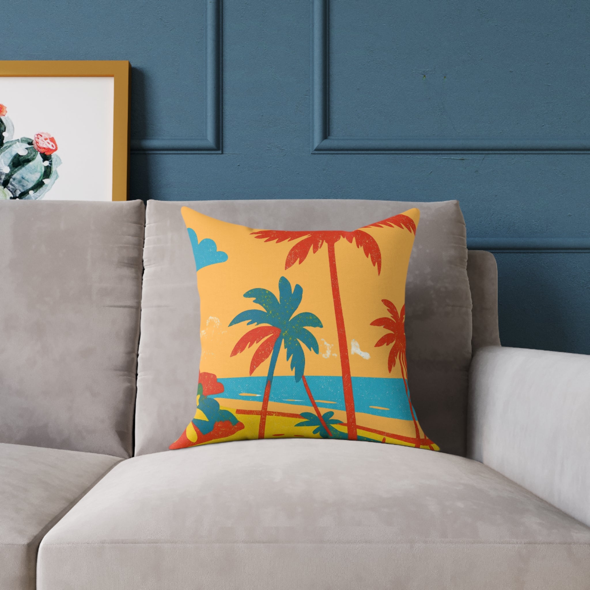 Colorful pillow with palm tree design on a gray sofa against a blue wall.