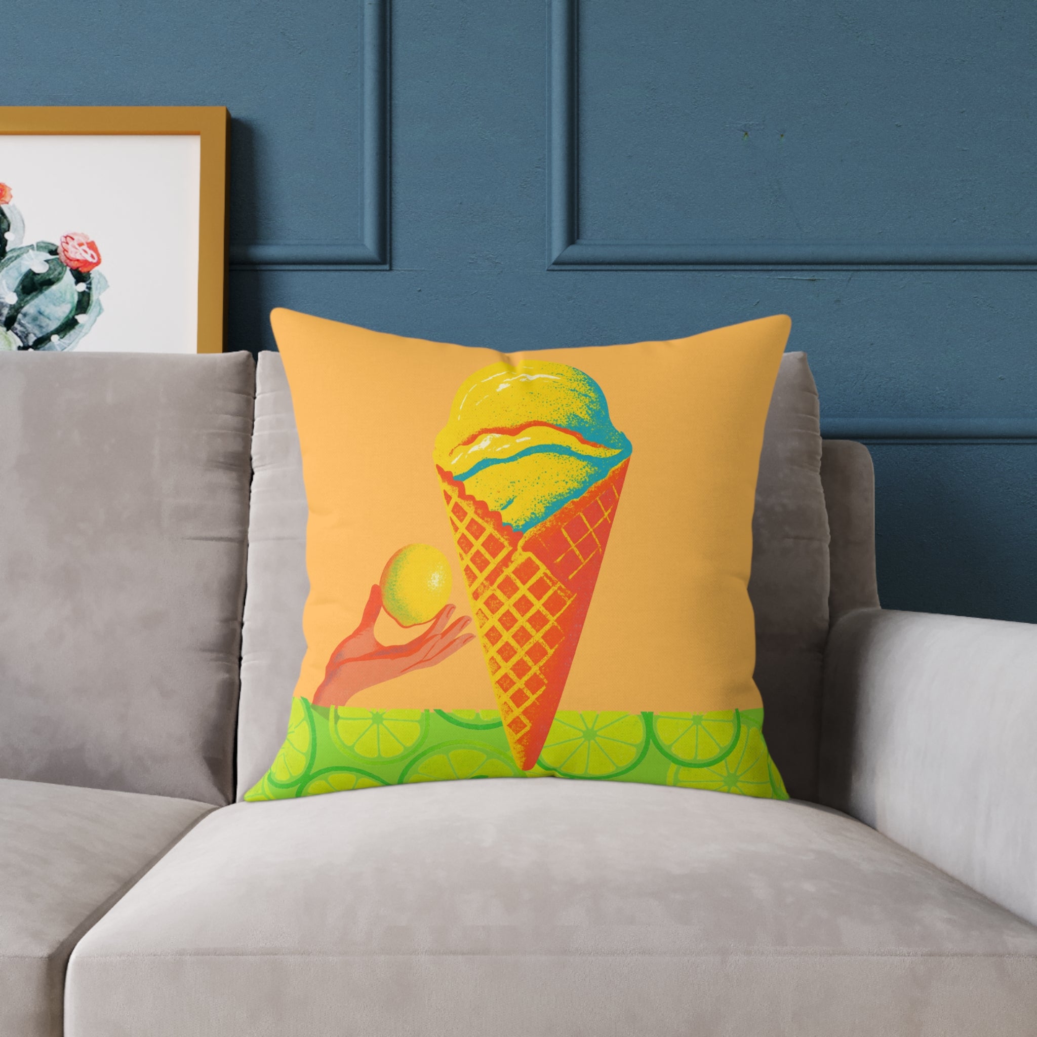 Decorative pillow with ice cream cone design on a gray sofa against a blue wall.