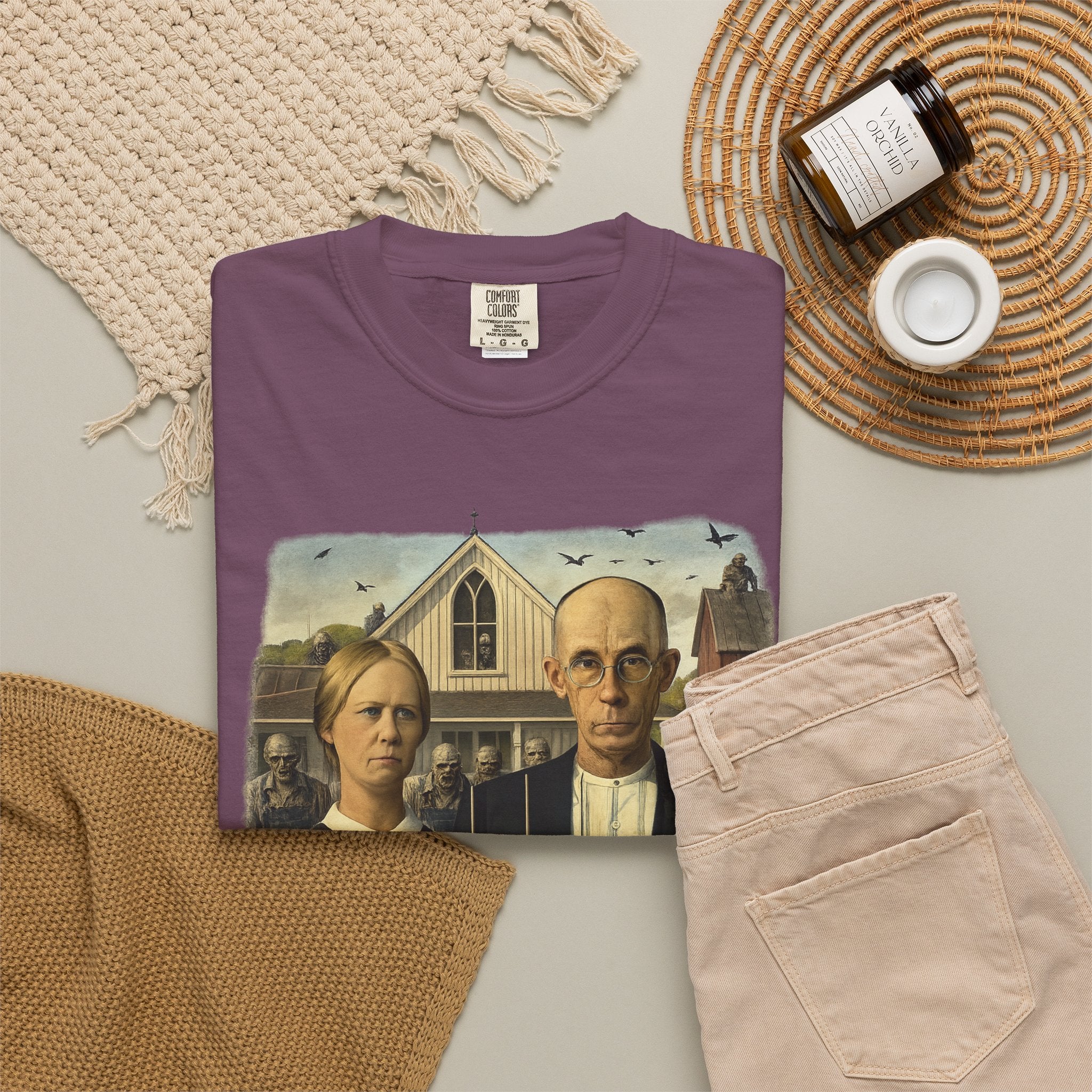 Folded burgundy t-shirt with reimagined image of zombies in American Gothic by Grant Wood on a white background