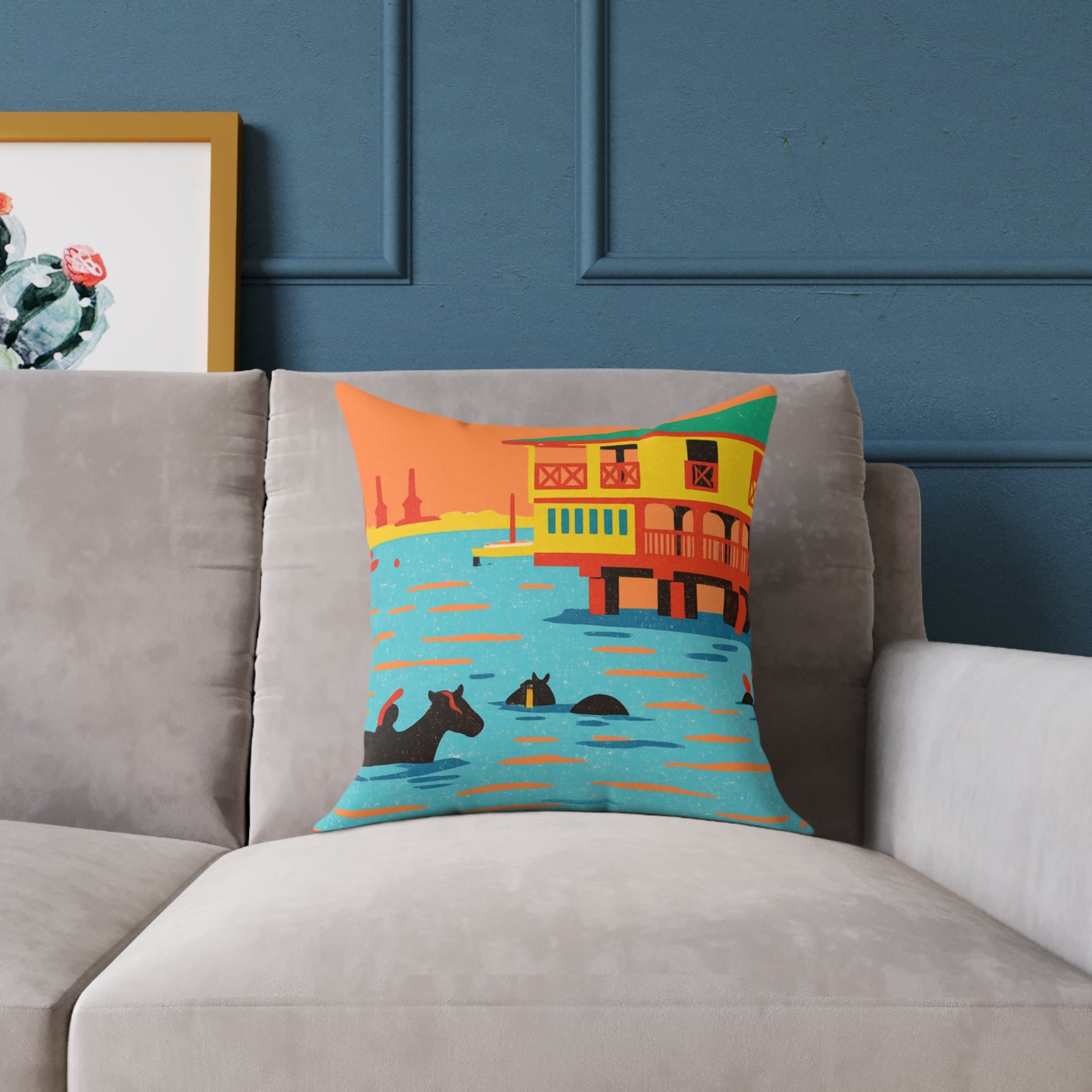 Decorative pillow with a colorful houseboat design on a gray sofa against a blue wall.
