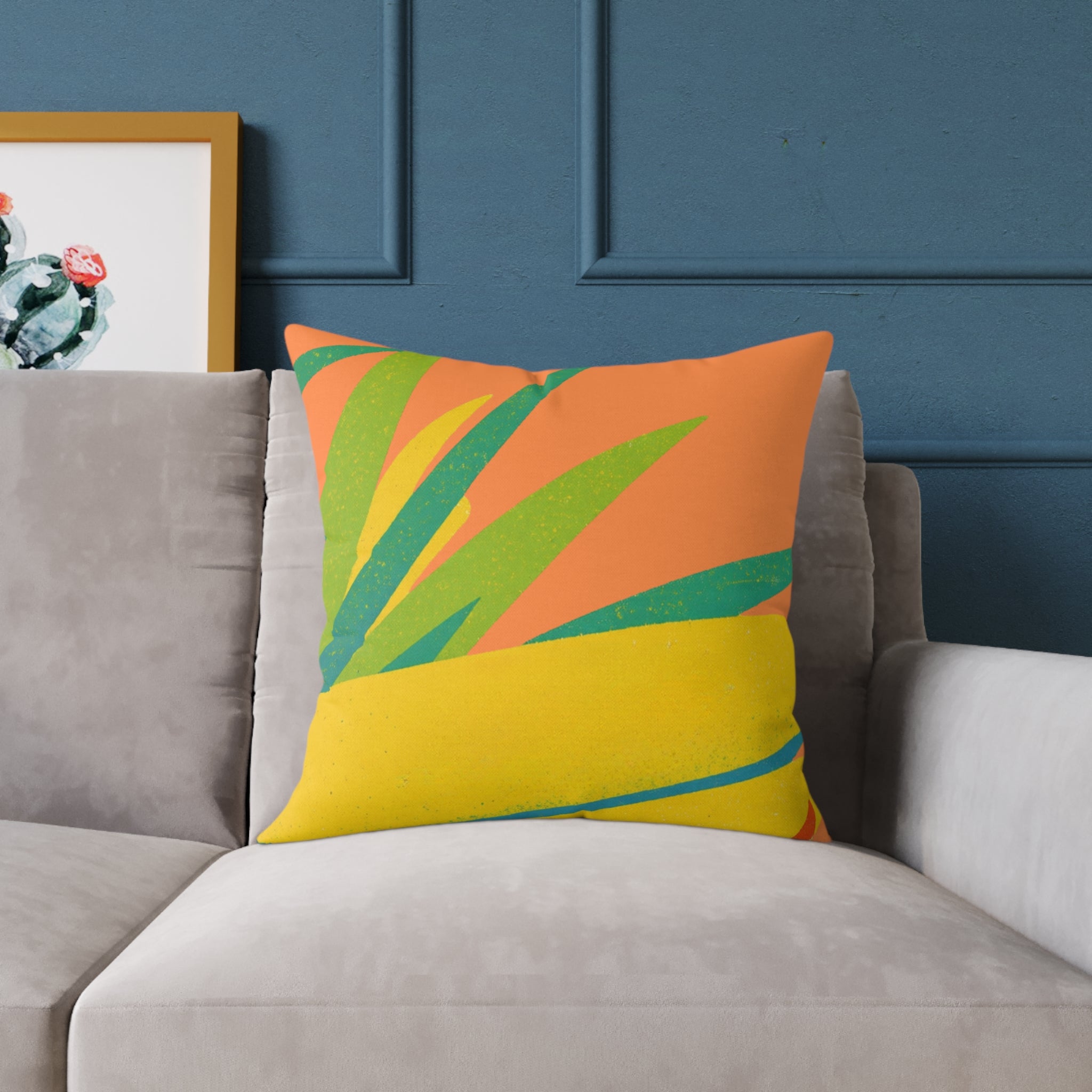 Colorful pillow with orange, green, and yellow design on a gray sofa against a blue wall.