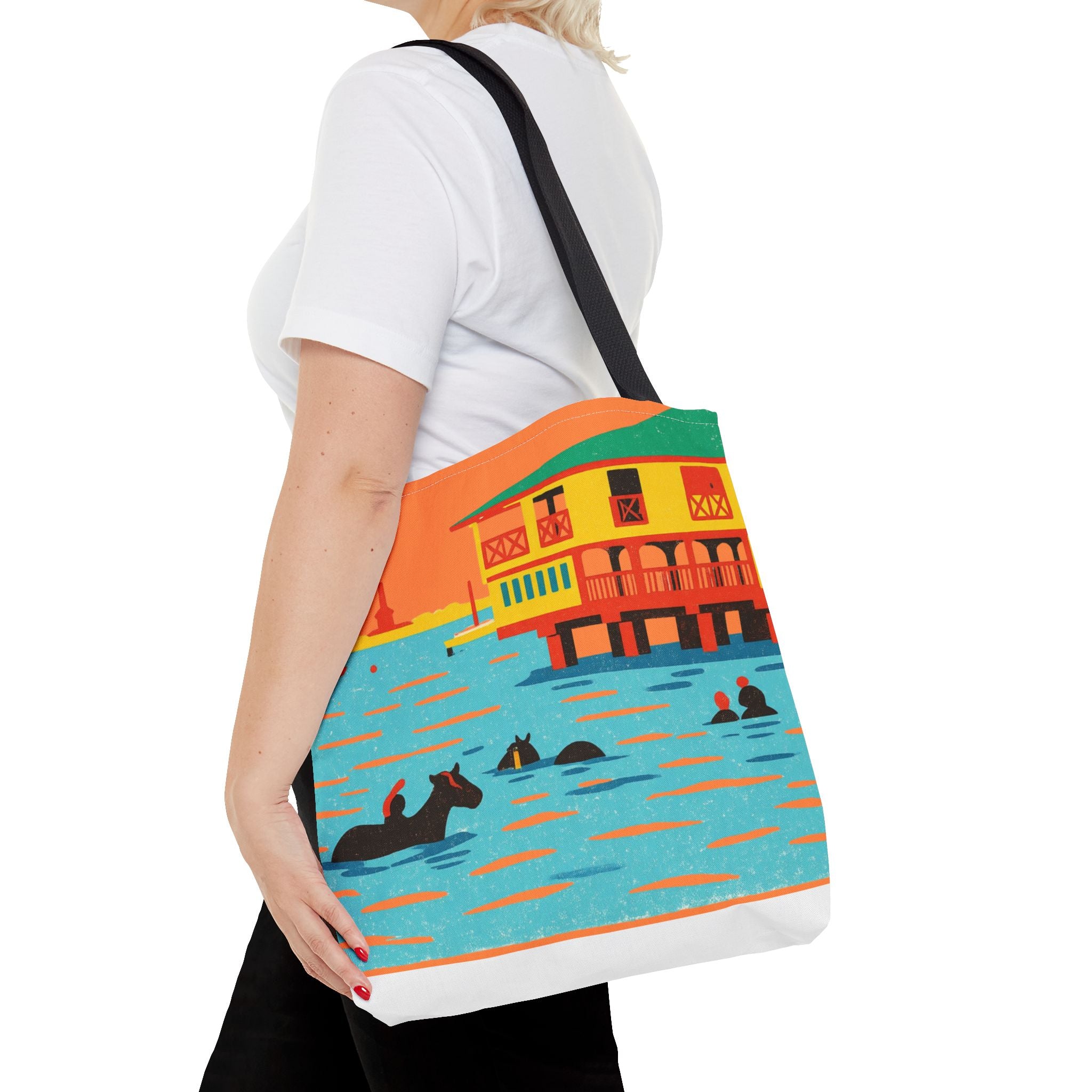 Person holding a tote bag with a colorful design of horses swimming in the sea at Pebbles Beach, Barbados