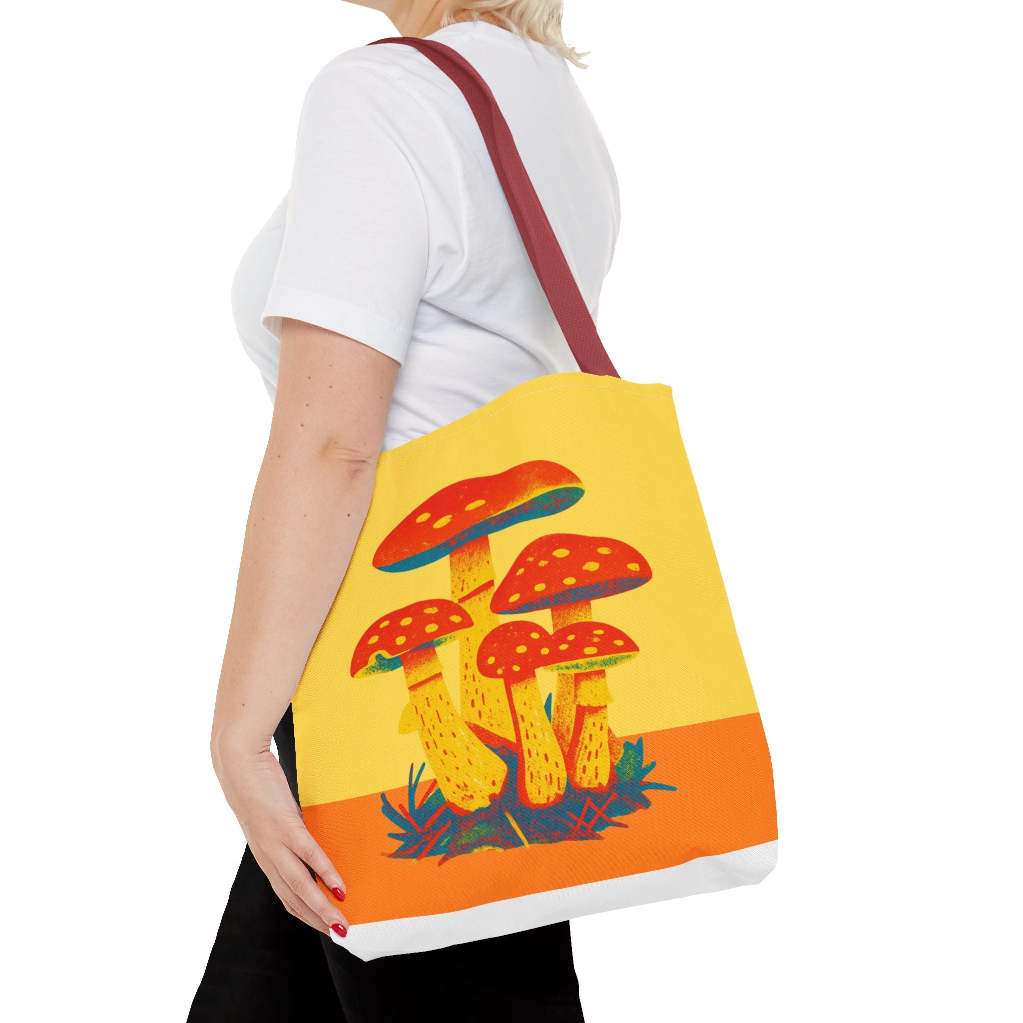 Person holding a tote bag with mushroom design on a white background