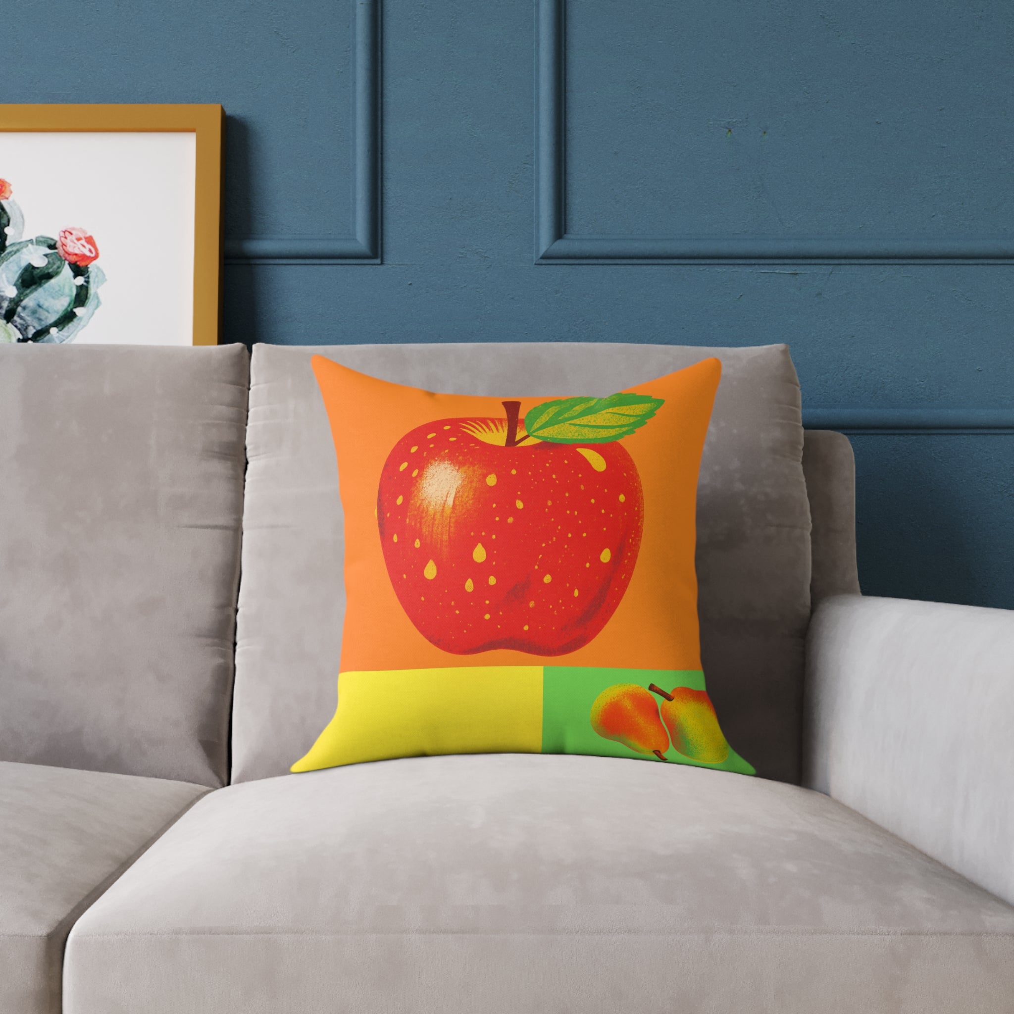 Decorative pillow with a red apple design on a gray sofa against a blue wall.