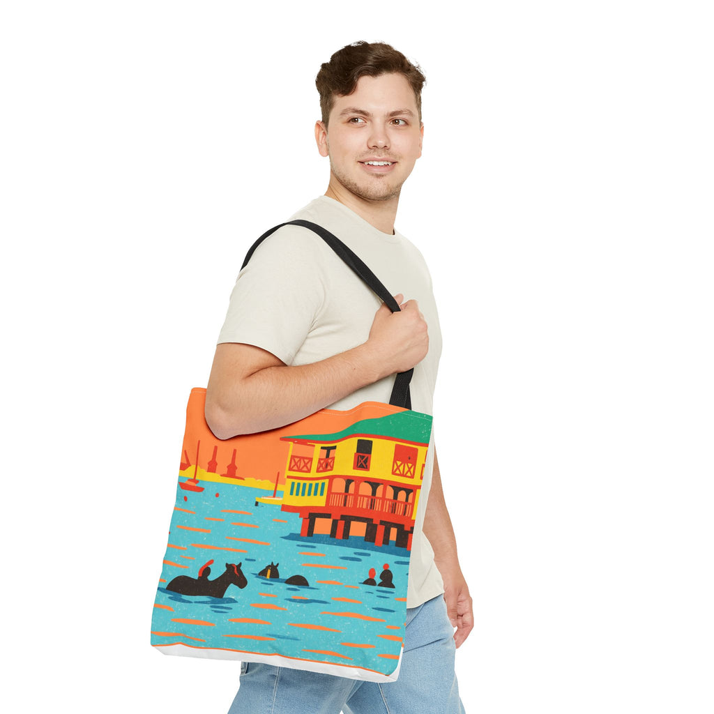 Man holding a colorful tote bag with a design horses swimming in the sea at Pebbles Beach, Barbados 