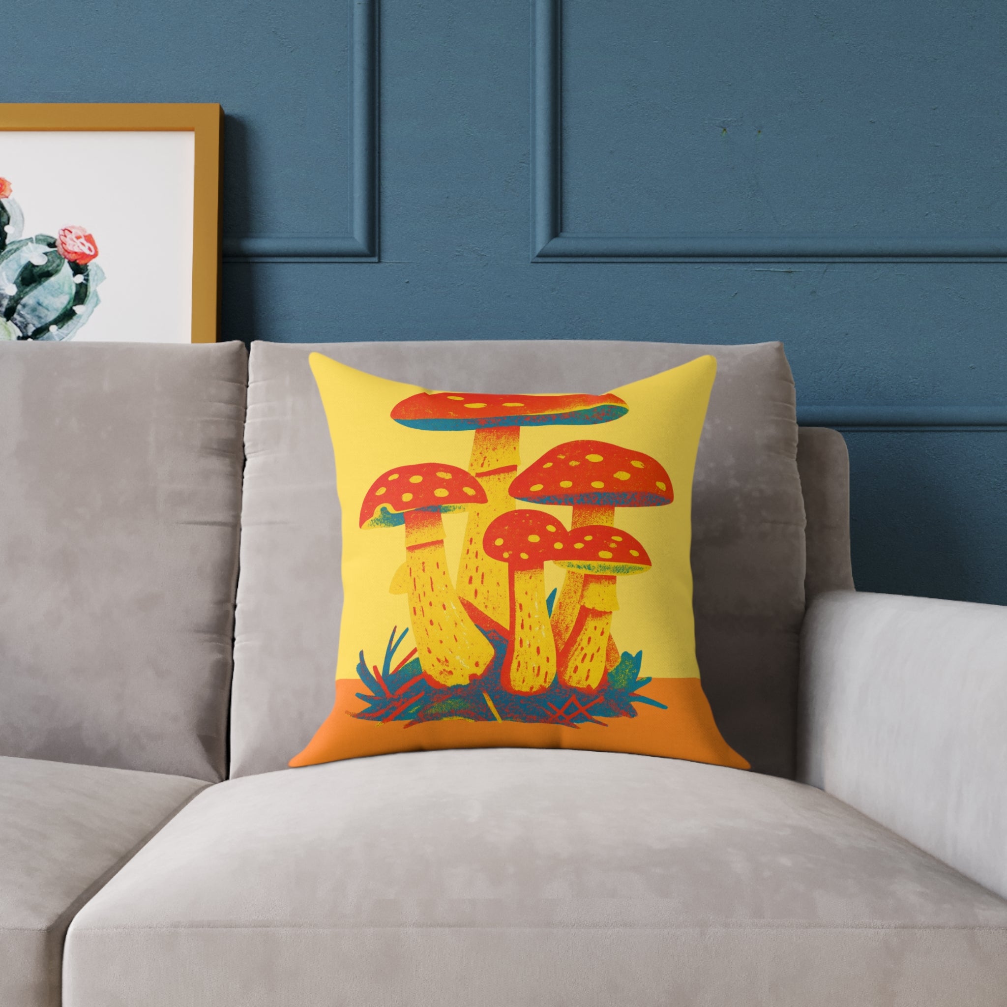 Decorative pillow with mushroom design on a gray sofa against a blue wall.