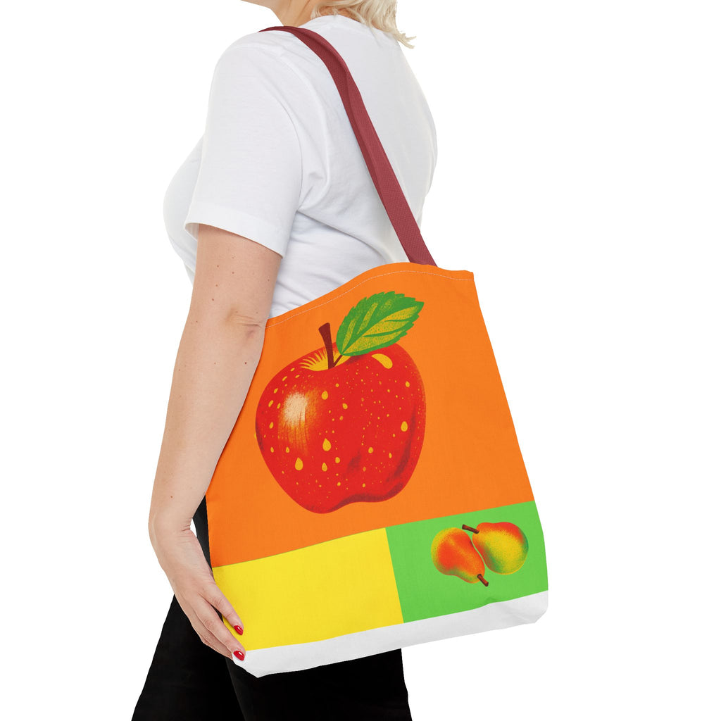 Person holding a tote bag with apple design on a white background