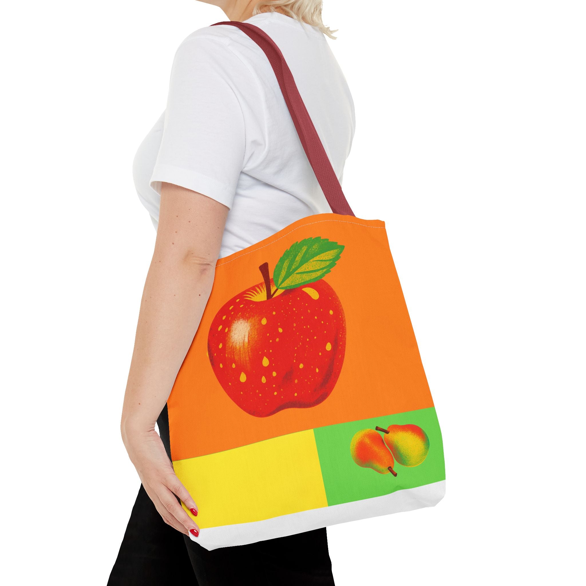 Person holding a tote bag with apple design on a white background