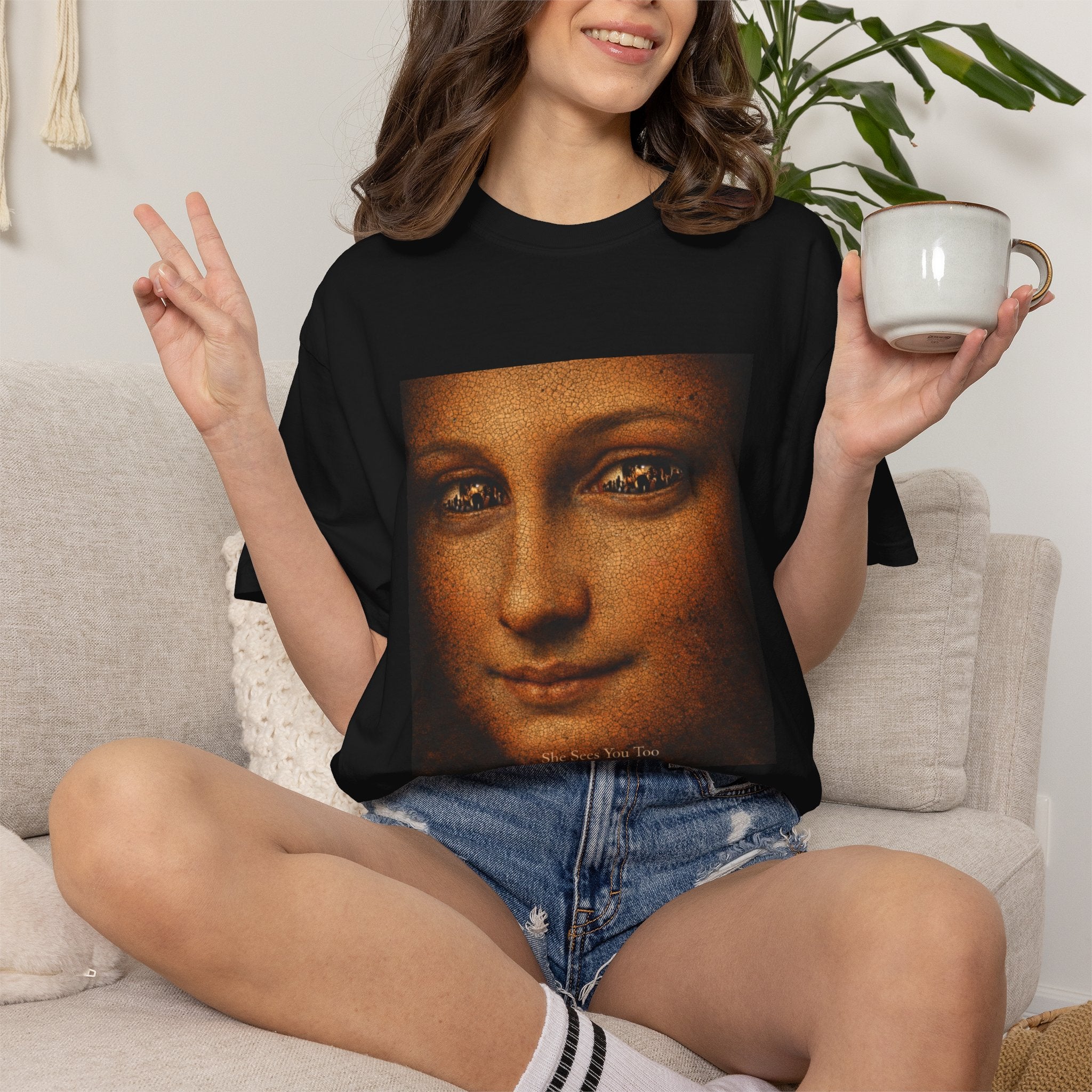 Woman sat down on a sofa wearing black t-shirt showing reimagined image of Da Vinci's Mona Lisa 