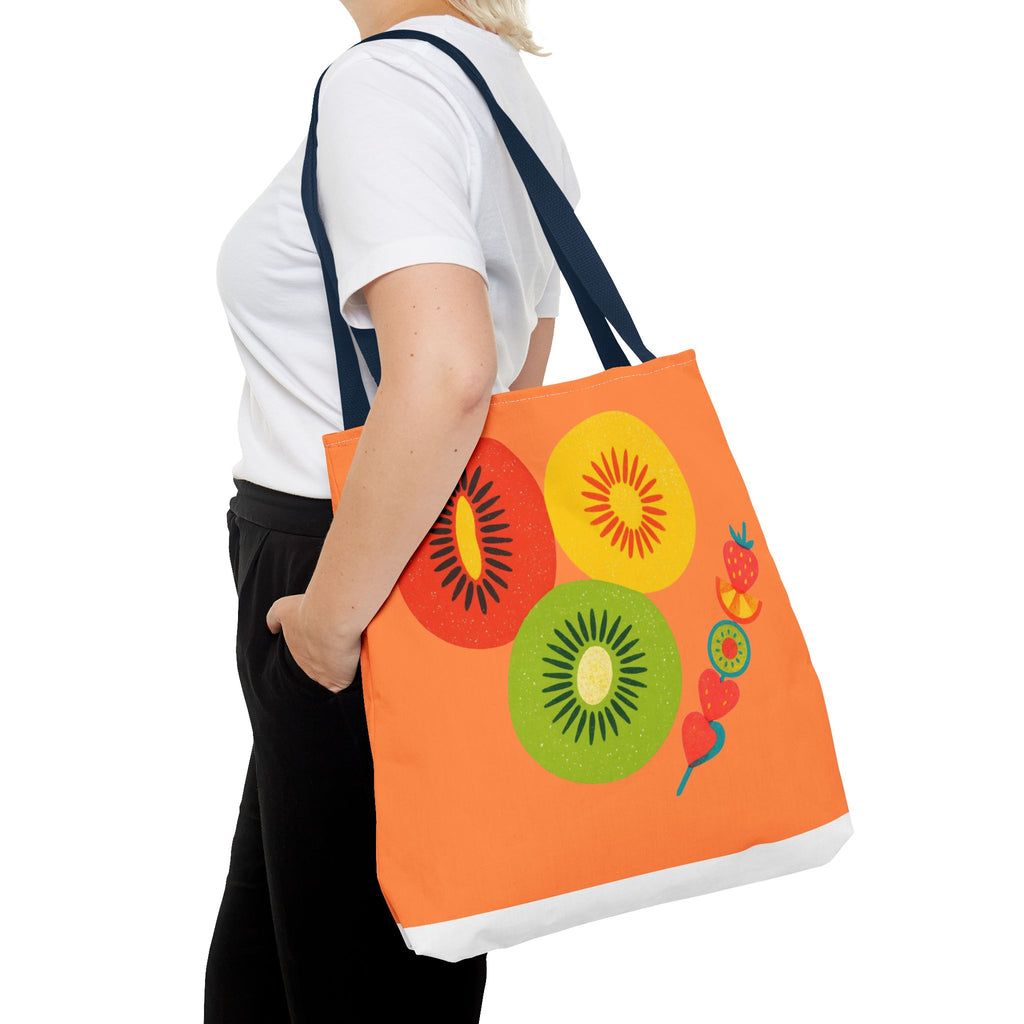 Person holding an orange tote bag with fruit designs on a white background