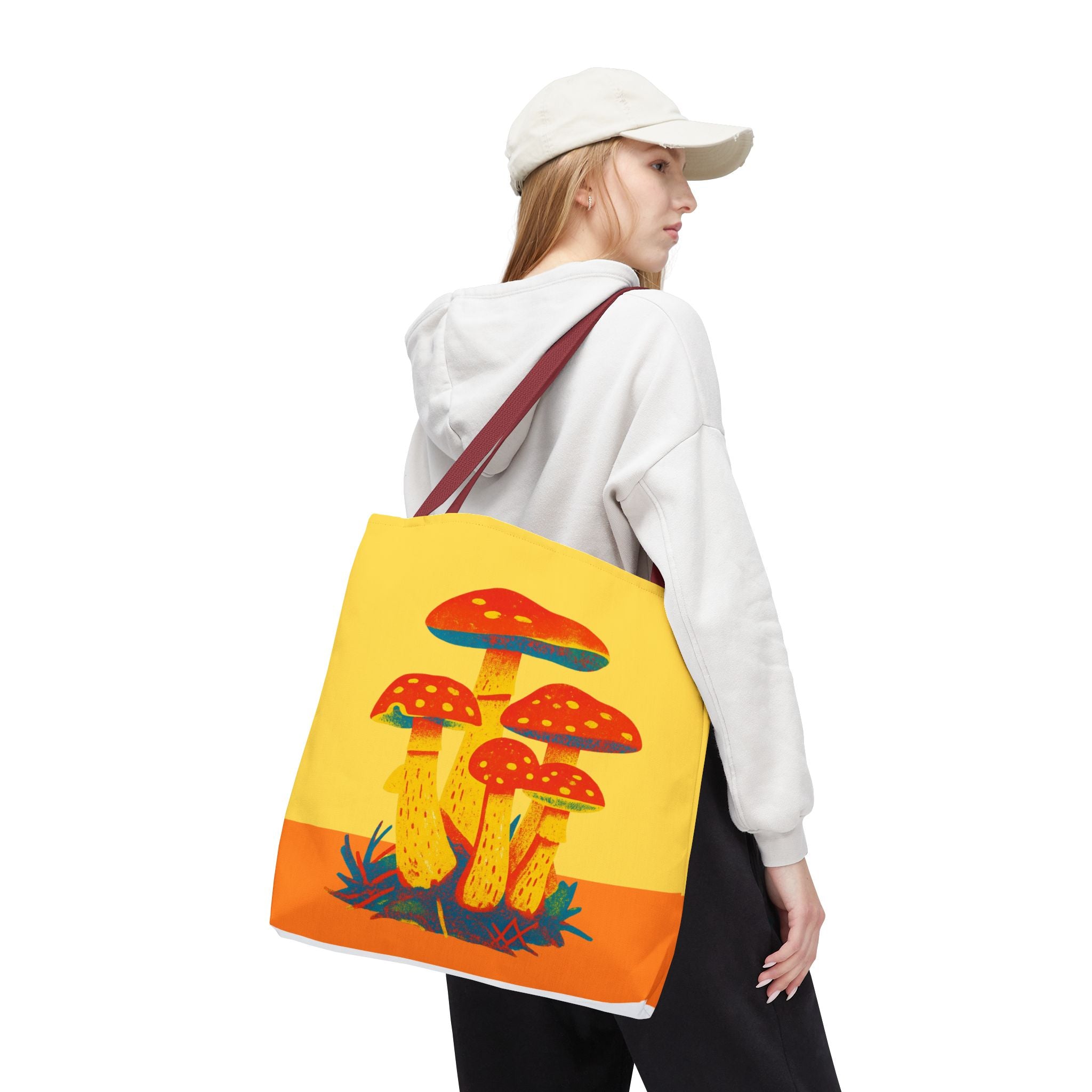 Person holding a tote bag with mushroom design on a white background