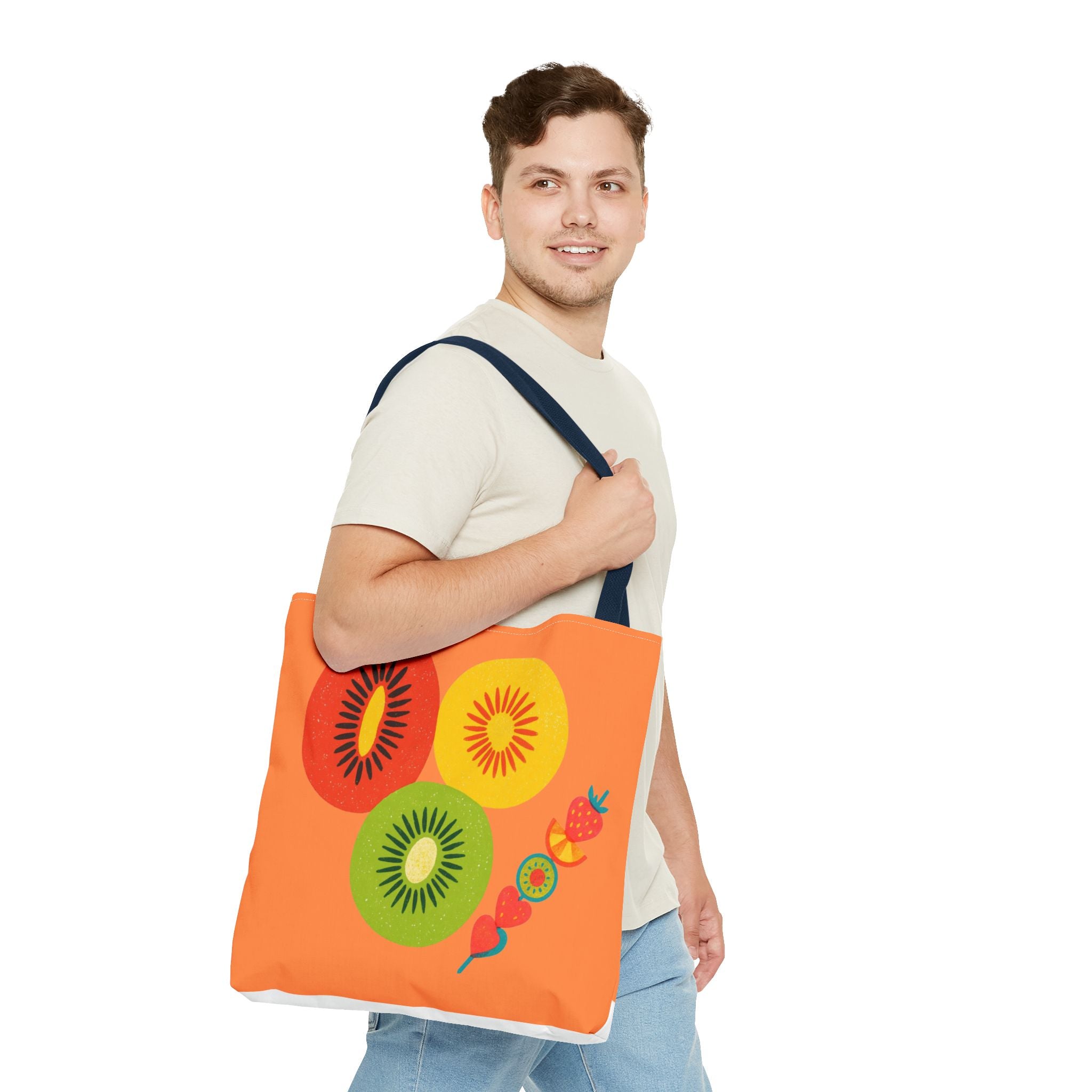 Man holding an orange tote bag with fruit designs on a white background