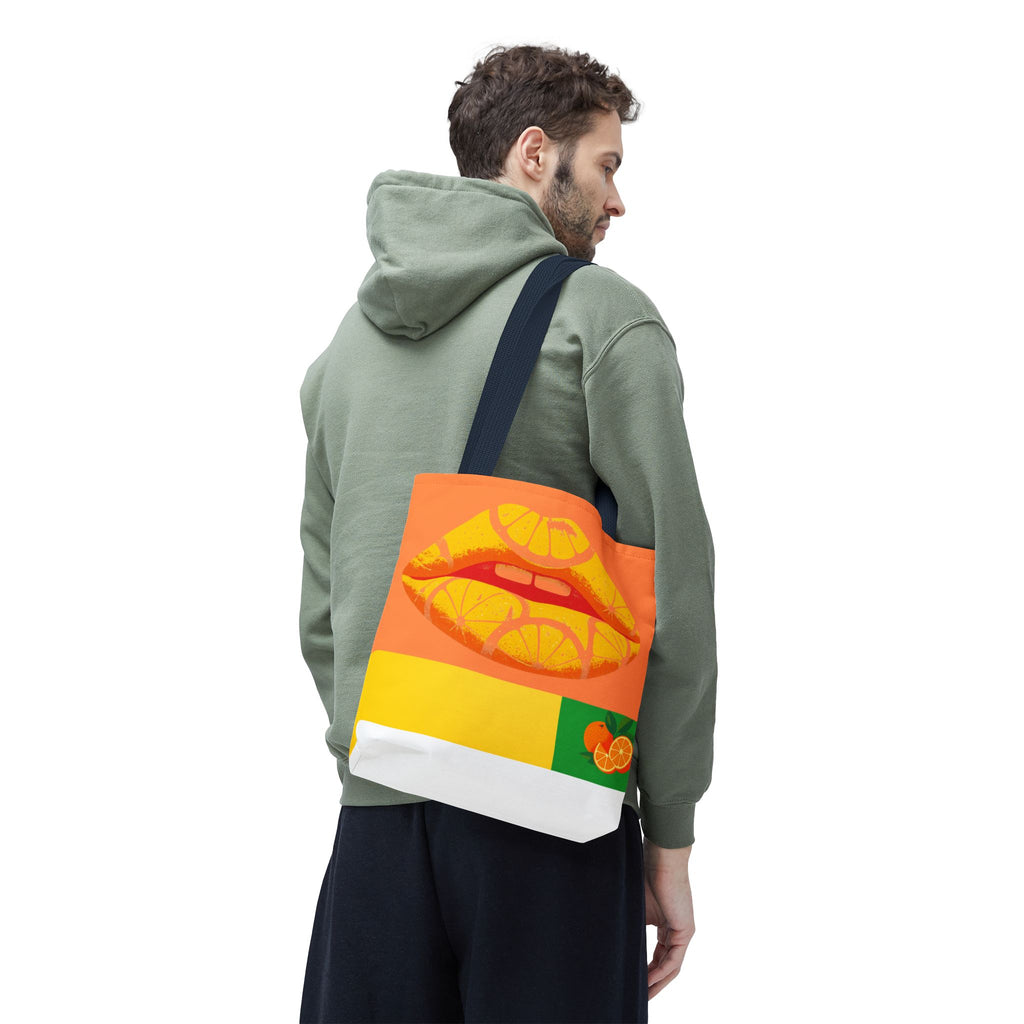 Person wearing a green hoodie with a colorful bag featuring lips and oranges on a white background