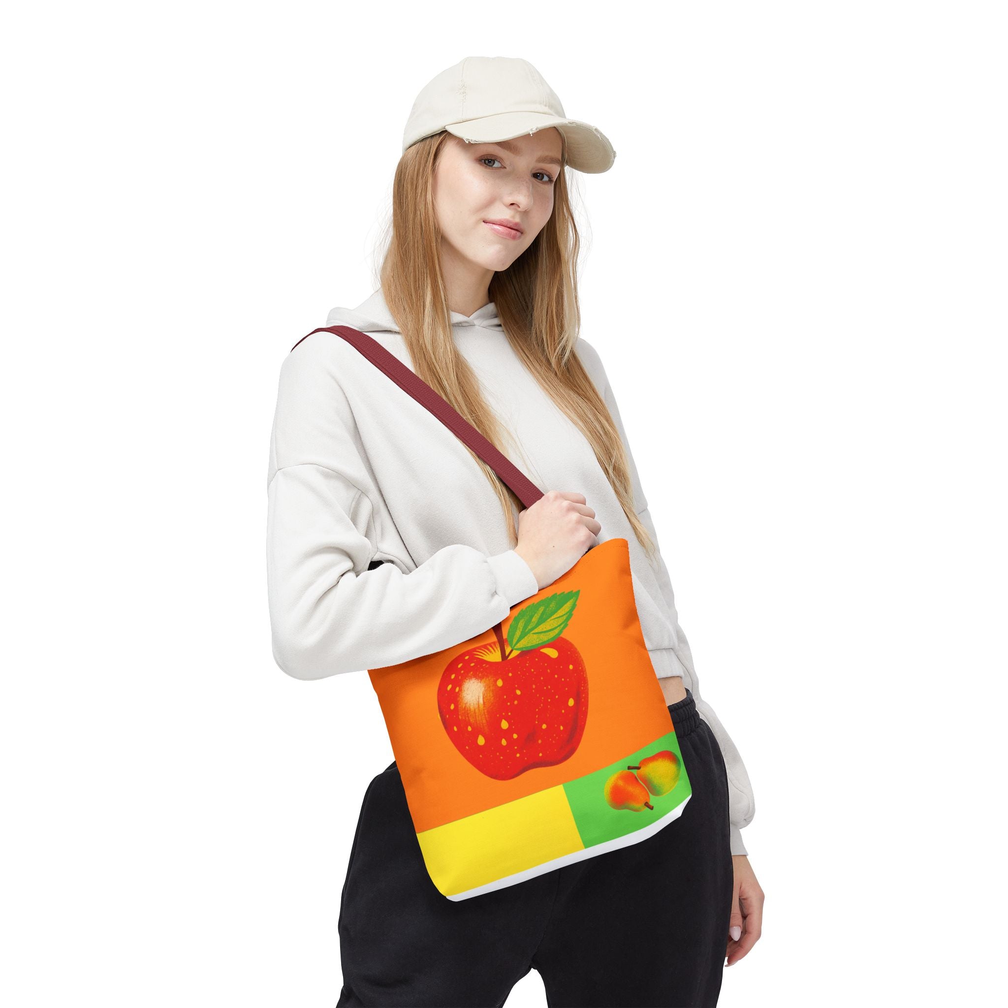 Person holding a tote bag with an apple design on a white background
