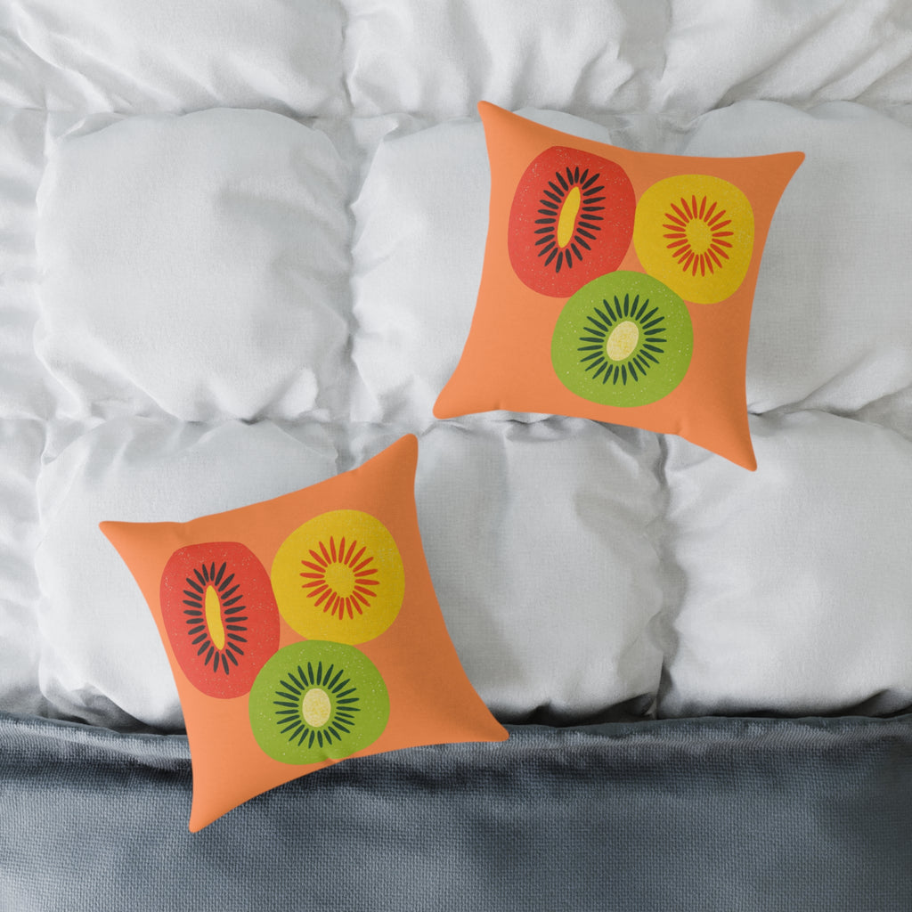Two orange pillows with kiwi fruit pattern on a bed with white pillows.