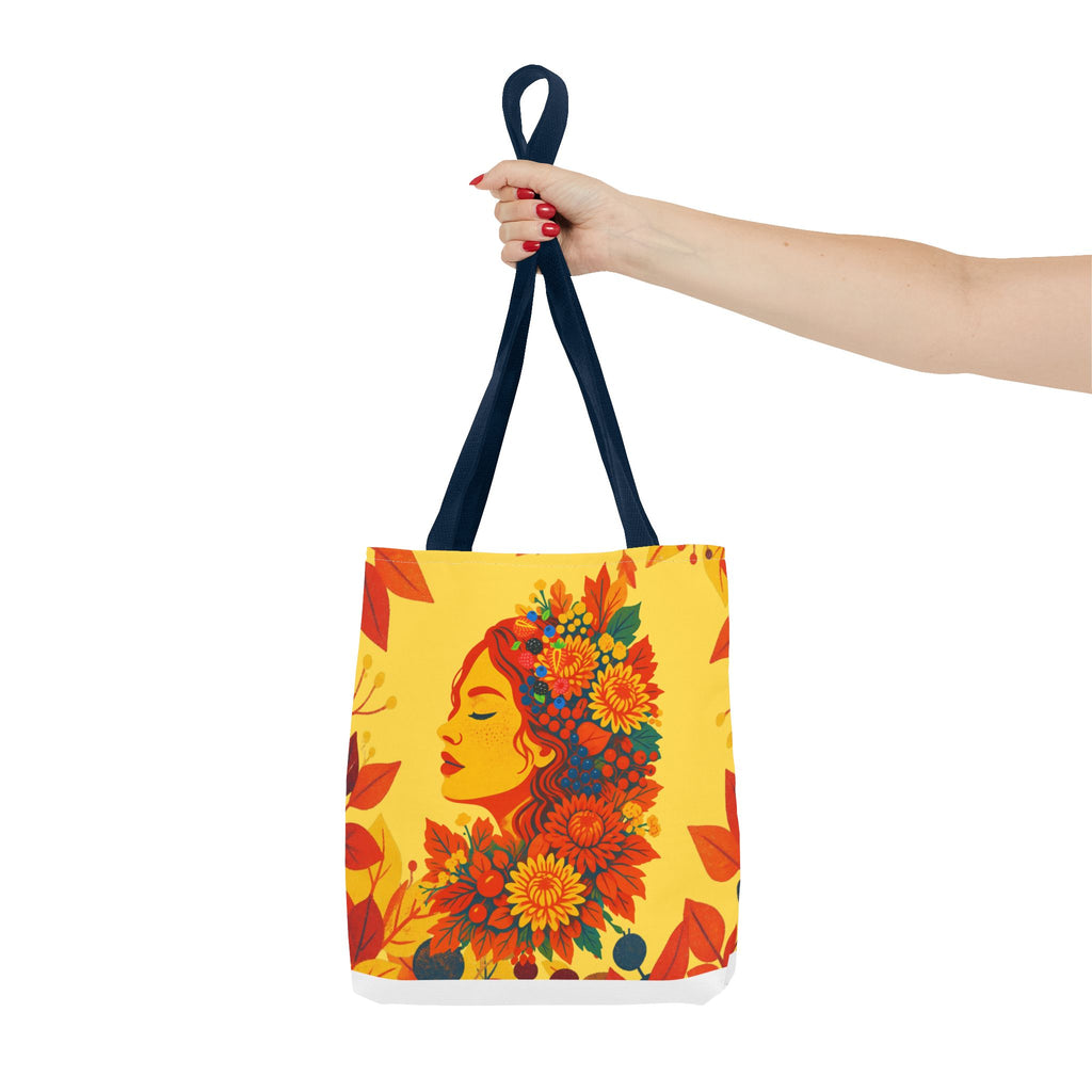 Tote bag with floral face design held by a hand on a white background