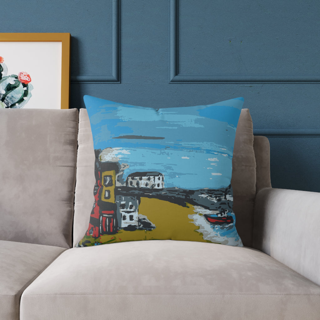 Decorative pillow with a colorful landscape design on a beige sofa against a blue wall.